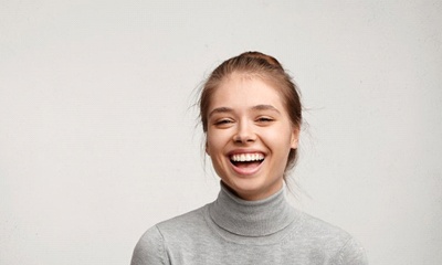 young woman in gray sweater laughing