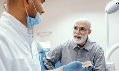 Dentist explaining implant-retained dentures in Wethersfield to male patient