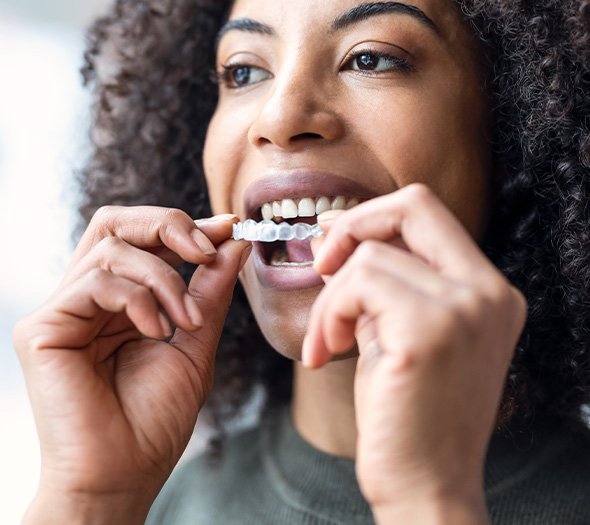 Smiling woman putting on clear aligner