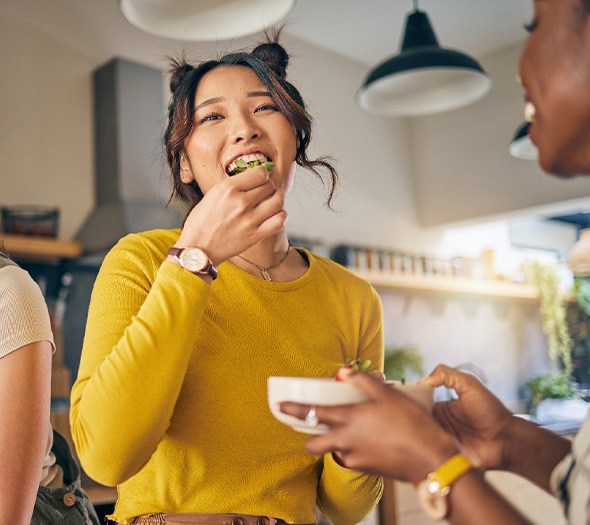 Woman smiling while eating with friends in kitchen