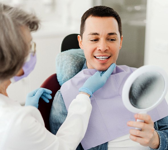 Man smiling at reflection in mirror with dentist