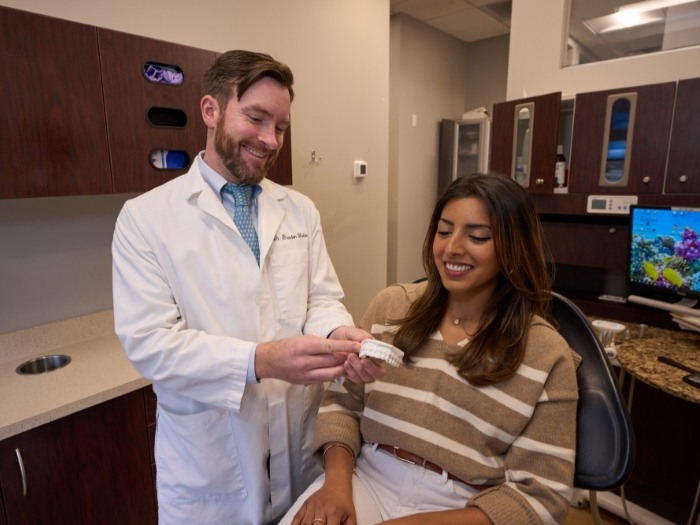 Dentist and patient looking at model of teeth