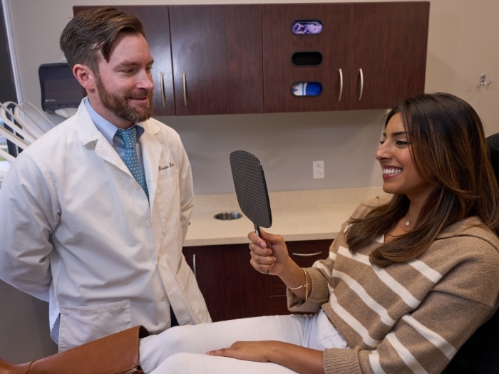 Dentist watching as patient looks at smile in mirror