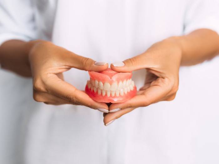 Lady presents viewer with dentures