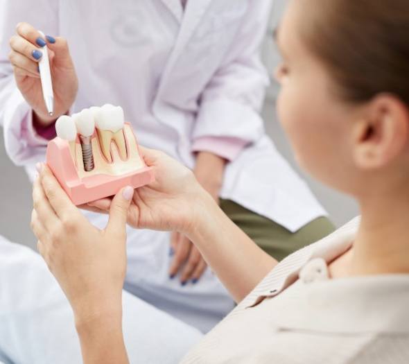 A patient holding onto a model of a dental implant