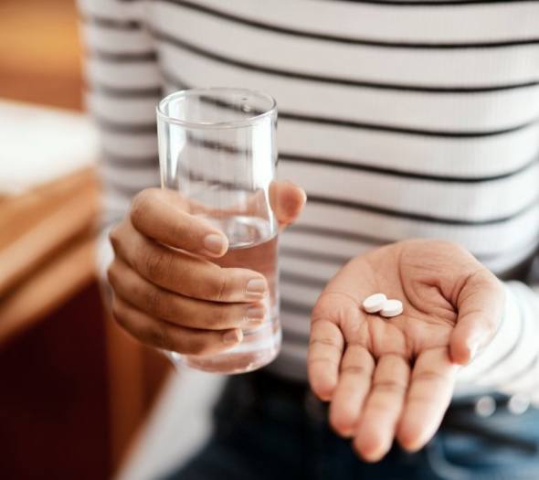 A person preparing to take pills with water