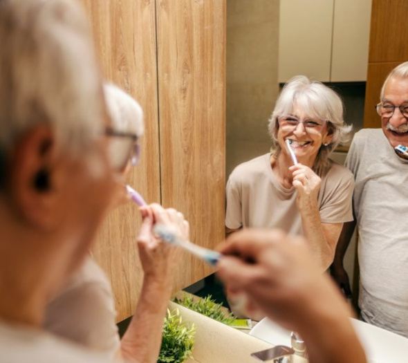 An older couple brushing their teeth together