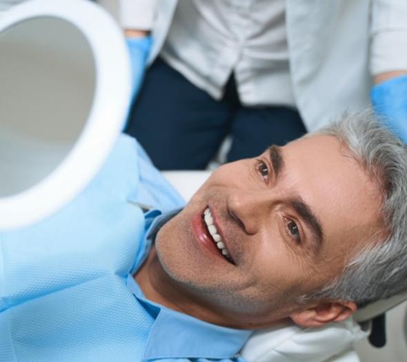 A patient checking his new dental implants with a mirror